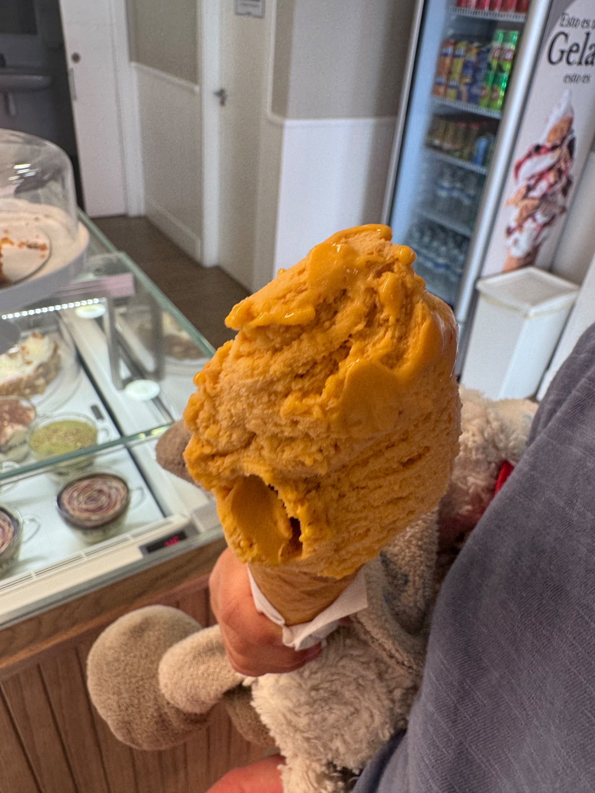 A mango gelato cone in front of the display case